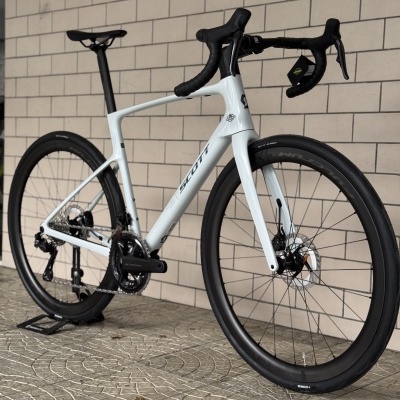 Bicicleta de estrada branca SCOTT com pneus SCHWALBE encostada a parede de azulejos.