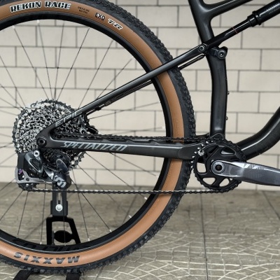 Parte traseira de bicicleta de montanha com quadro preto e pneus bege e preto