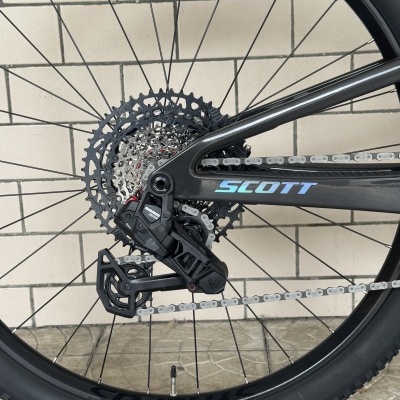 Roda traseira preta de bicicleta com componentes metálicos e logo SCOTT em azul no quadro.