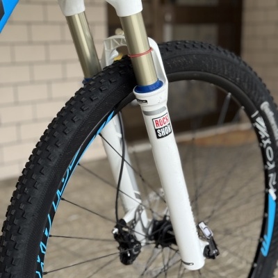 Roda dianteira de bicicleta de montanha com suspensão RockShox branca e aro preto com detalhes azuis