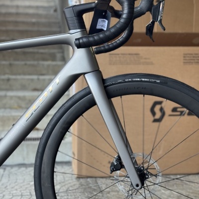 Bicicleta de estrada cinzenta com guiador curvo preto e pneus Schwalbe One dianteiros