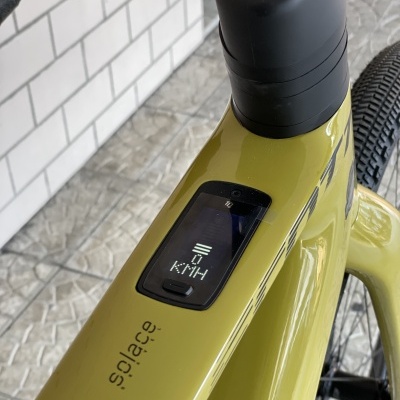 Bicicleta elétrica verde musgo com ecrã digital indicador de velocidade e texto solace no quadro