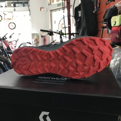 Sola vermelha de sapato desportivo sobre caixa preta com logo SCOTT numa loja de bicicletas