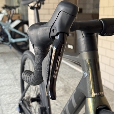 Bicicleta de estrada preta com manete Shimano 105 e fita preta no guiador