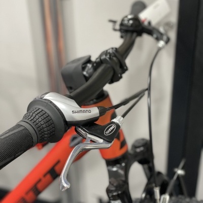 Punho de bicicleta preto com manete e comando Shimano preto e prateado, quadro laranja e preto