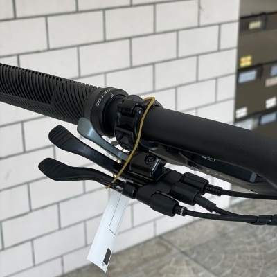 Manete de bicicleta preta com alavancas e cartão branco preso com borracha amarela