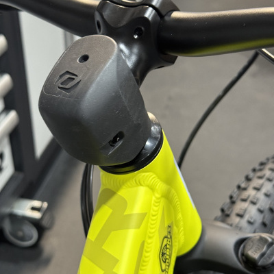 Parte da frente de uma bicicleta amarela com guiador preto e suporte preto