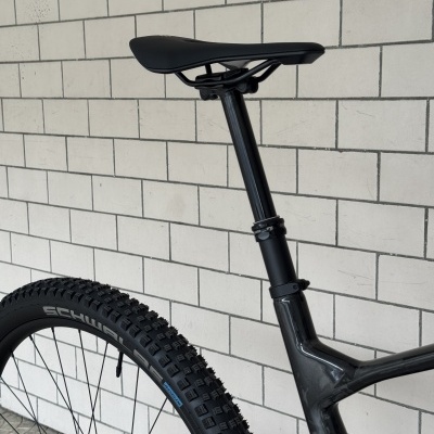Detalhe de bicicleta preta com banco e pneu Schwalbe junto a parede de azulejos brancos