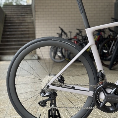 Parte traseira de uma bicicleta de estrada branca com rodas pretas e selim preto