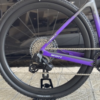 Roda traseira de bicicleta roxa e preta com pneu SCHWALBE G-ONE RX e transmissão XPLR