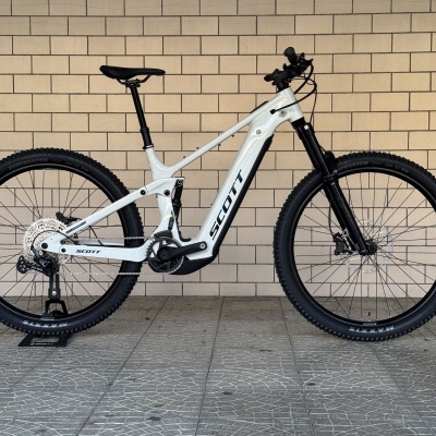 Bicicleta de montanha branca SCOTT encostada numa parede de azulejos bege