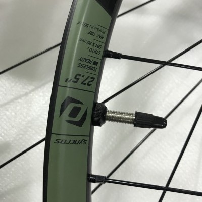 Roda de bicicleta com aro preto e verde e válvula de ar visível