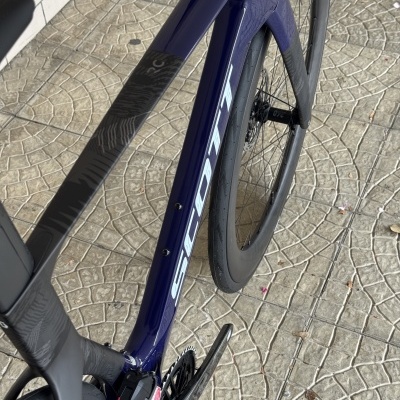 Bicicleta de estrada azul escuro com roda de carbono e texto SCOTT no quadro