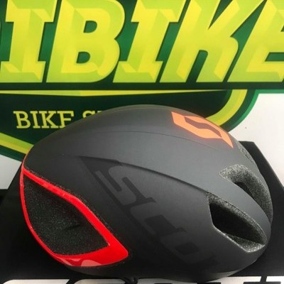 Capacete ciclismo preto com vermelho e logo Scott laranja em fundo com cartaz BIKE