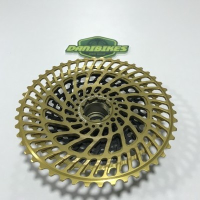 Cassete de bicicleta dourada em metal com design circular perfurado e núcleo preto