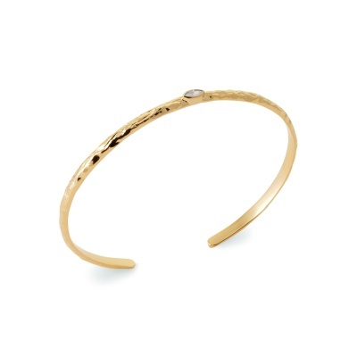 Pulseira dourada martelada com pedra oval transparente.