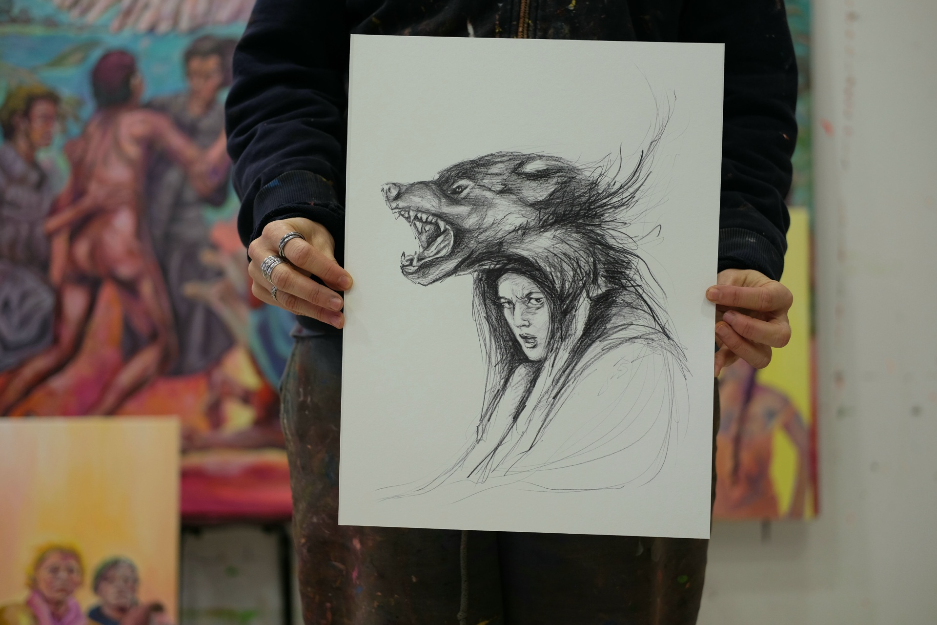 Piece of My Heart - PRINT Desenho a carvão de mulher com capuz de pele de lobo, segura por pessoa em estúdio de arte com pinturas ao fundo