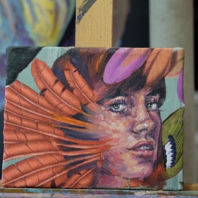 Retrato artístico em tela com retrato de mulher em tons laranja, roxo e verde