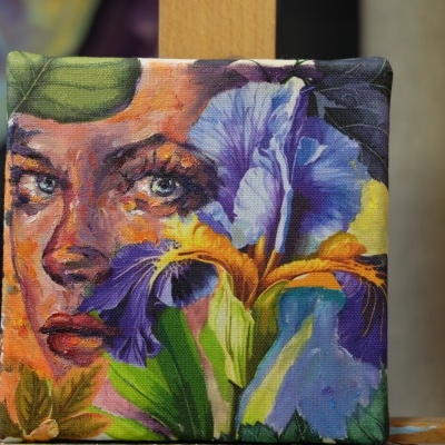 Tela colorida com pintura de rosto e flores em suporte de madeira