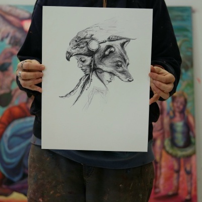 Desenho a preto e branco de rosto humano com cabeça de lobo, segurado por pessoa em estúdio de arte