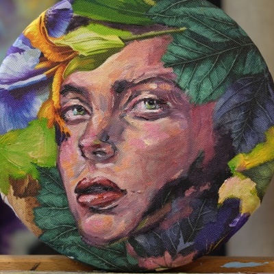 Objeto redondo com estampa artística de rosto feminino entre folhas coloridas