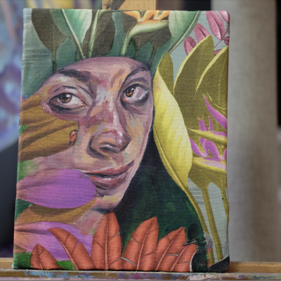 Livro com capa ilustrada mostrando rosto de mulher rodeado por folhas coloridas