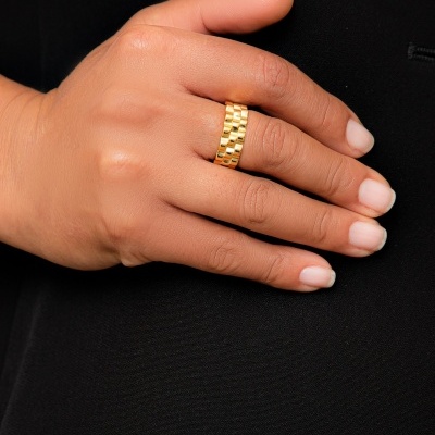 Mão feminina com anel dourado de textura malha