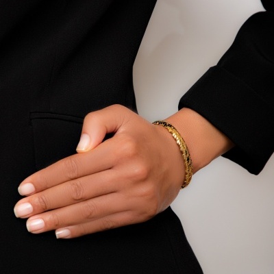 Mão feminina com pulseira dourada vestindo casaco preto