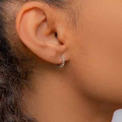 Brinco prata tipo argola com textura de bolas na orelha esquerda