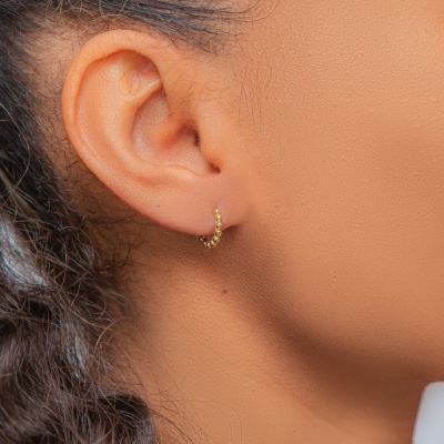 Brinco argola dourado com bolinhas na orelha de mulher com cabelo castanho