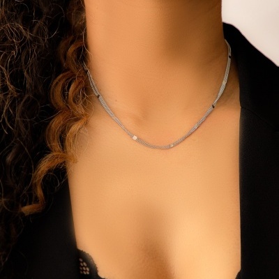 Colar prateado delicado num pescoço com blazer preto e top de renda preta