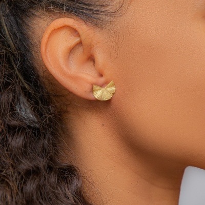 Brinco dourado meia-lua texturizado na orelha de mulher