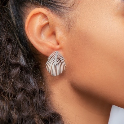 Brinco prateado em forma de folha ou pena numa orelha feminina