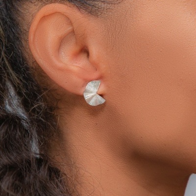 Brincos semicirculares prateados texturizados usados na orelha