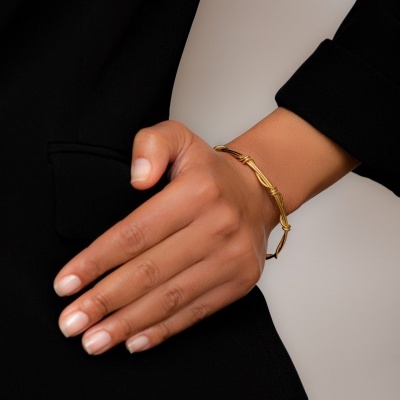 Pulseira dourada fina em pulso de mão com jaqueta preta