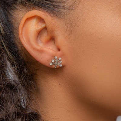 Brinco prateado com pedras brilhantes em forma de flor na orelha de mulher