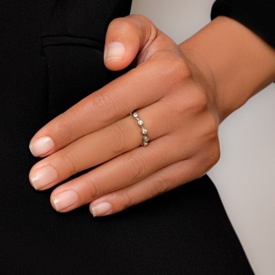 Mão com anel prateado esférico sobre casaco preto