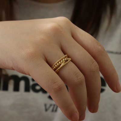 Mão com anel dourado trançado em dedo anelar