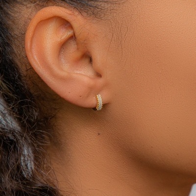 Brinco argola dourado texturizado numa orelha feminina