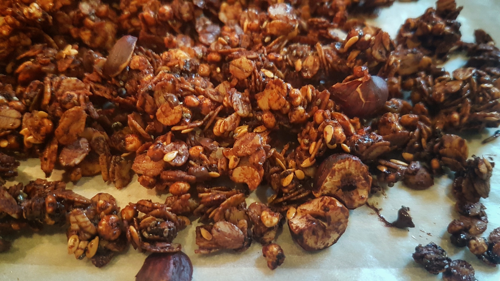 Granola caseira castanha escura com pedaços de nozes sobre papel vegetal
