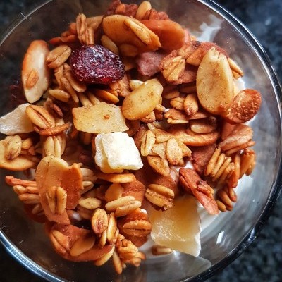 Taça de vidro com granola mista contendo aveia, castanhas e frutas desidratadas
