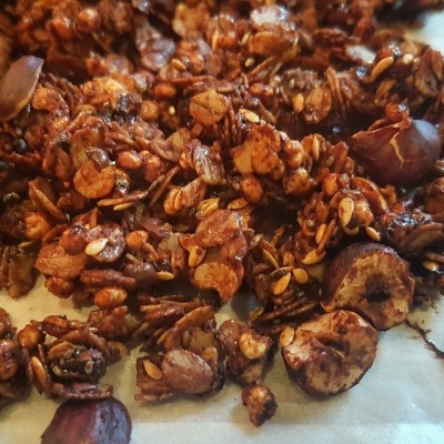Granola caseira castanha escura com pedaços de nozes sobre papel vegetal