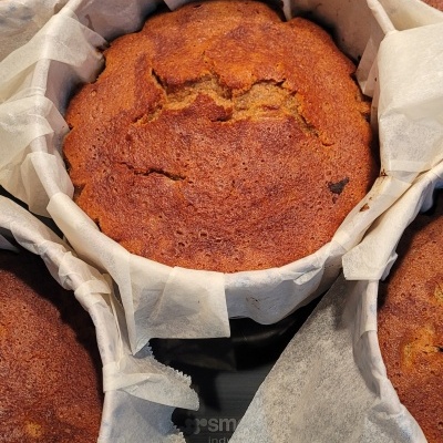 Bolos redondos castanhos em formas com papel vegetal branco sobre bancada cinzenta