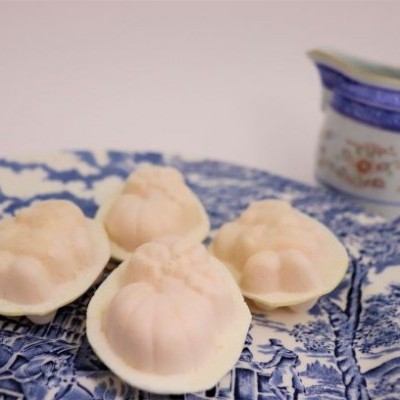 Doces em formato de frutos num prato azul e branco com jarra pequena ao lado