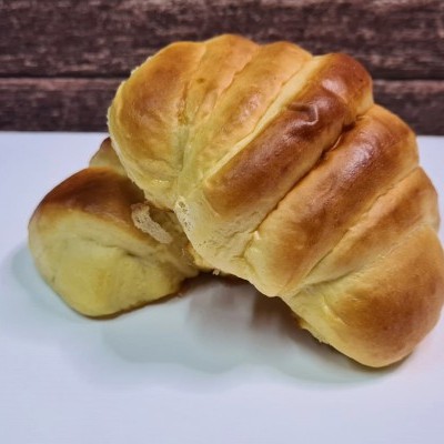 Dois croissants dourados sobre uma superfície branca com fundo de madeira escura