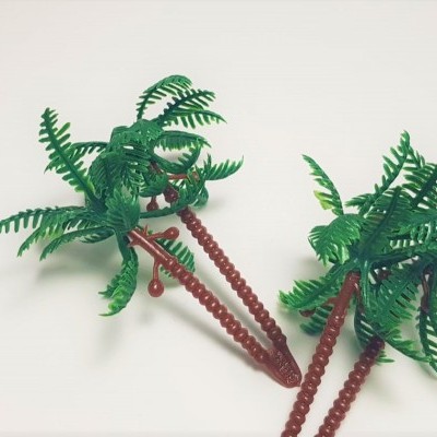 Duas pequenas palmeiras decorativas de plástico com folhas verdes e troncos castanhos