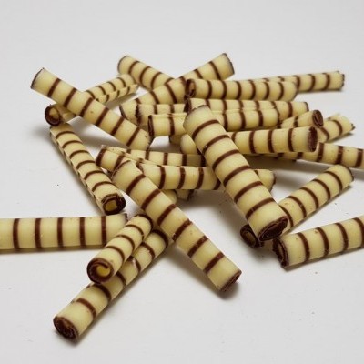 Rolhas finas de chocolate branco com riscas marrons dispostas numa superfície branca