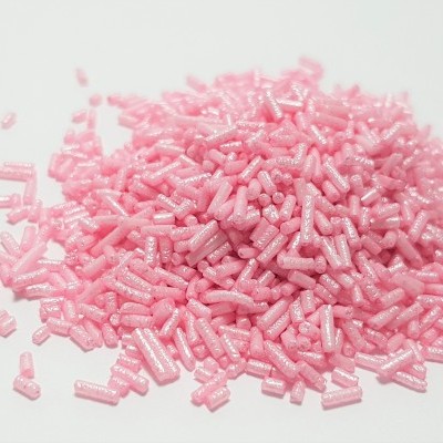 Confeitos açucarados rosa cilíndricos brilhantes sobre fundo branco