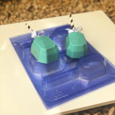 Dois sabonetes azuis octogonais com palhinhas e laços sobre embalagem plástica azul