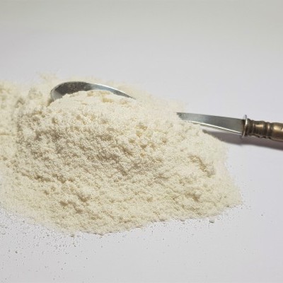 Pó branco com colher metálica e cabo decorado numa superfície branca